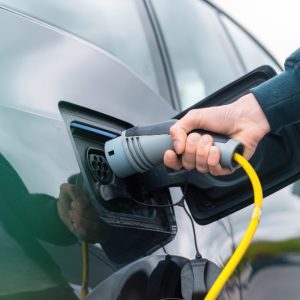 man-plugging-charger-into-electric-car-charge-station